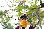 Woman covering face with hibiscus leaf in autumn