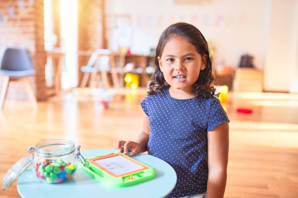 istock Beautiful toddler girl drawing cute draw using digital board at kindergarten 1186061899