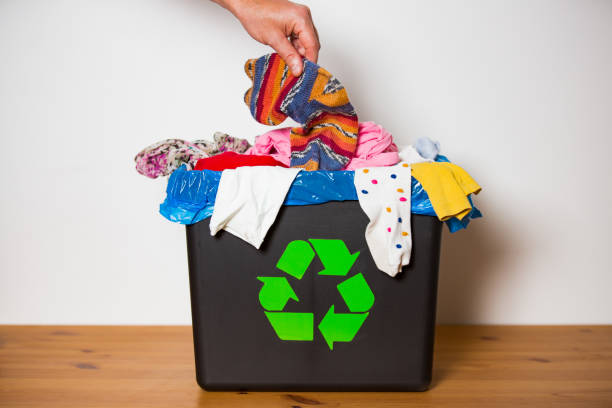 istock Hand putting used sock in bin with recycling sign. 1186063826