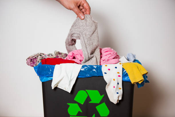 istock Hand putting used sock in bin with recycling sign. 1186064180