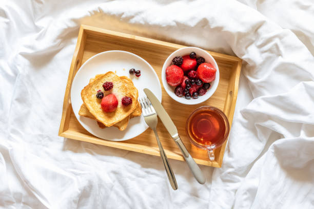 화창한 아침에 침대에서 아름다운 밝은 아침 식사. 트레이에 딸기와 차 한 잔과 함께 토스트. 평온의 개념, 진정, 주말, 엄마, 사랑하는 여성을위한, 호텔에서 아침 식사 - red bed 뉴스 사진 이미지