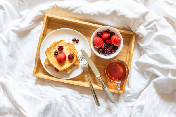 beautiful bright breakfast in bed on a sunny morning. toast with berries and a cup of tea on a tray. concept of tranquility, calm, weekend, for mom, for the beloved woman, breakfast at the hotel - close up directly above holiday nobody imagens e fotografias de stock