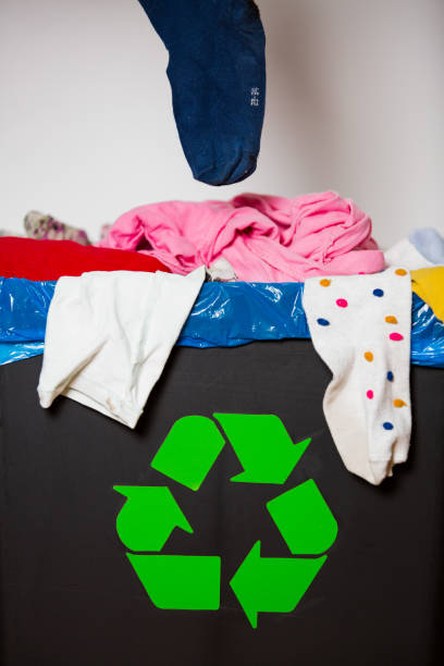 istock Hand putting used sock in bin with recycling sign. 1186064938