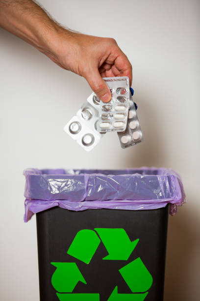 istock Hand putting expired medicine packages into bin with recycling sign 1186065735