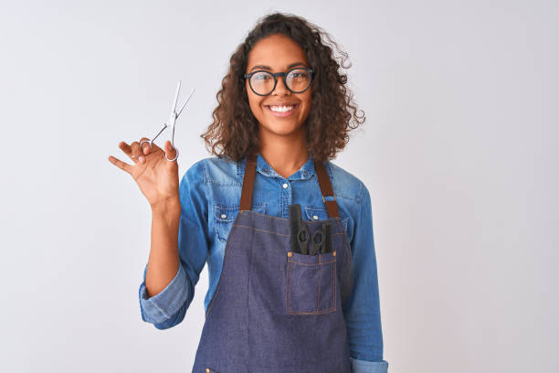 jeune femme brésilienne de coiffeur utilisant des ciseaux restant au-dessus du fond blanc d'isolement avec un visage heureux restant et souriant avec un sourire confiant affichant des dents - toothy smile relaxation white healthcare and medicine photos et images de collection