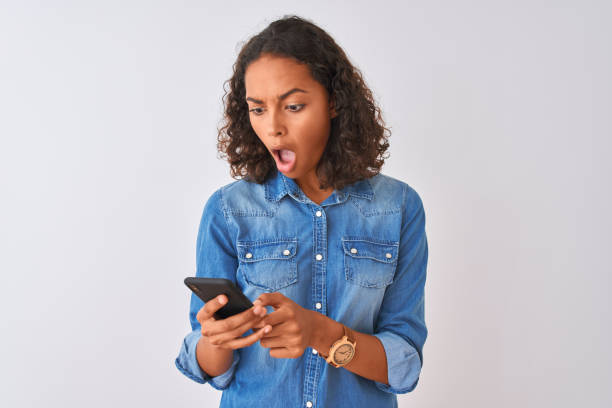 istock Young brazilian woman using smartphone standing over isolated white background scared in shock with a surprise face, afraid and excited with fear expression 1186065965