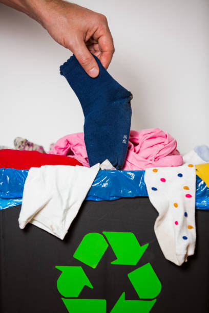 istock Hand putting used sock in bin with recycling sign. 1186066125