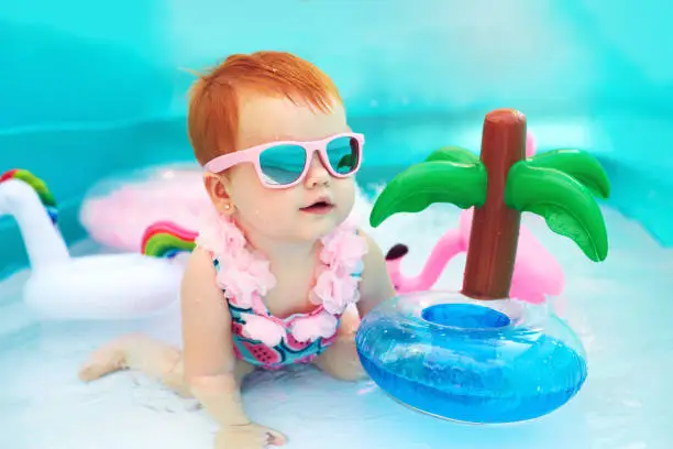Photo of cute happy baby girl having fun in kid pool, summer vacation