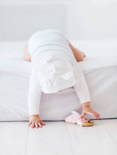 cute infant baby girl going down from the bed, nine month old cute infant baby girl going down from the bed, nine month old Regression in babies stock pictures, royalty-free photos & images