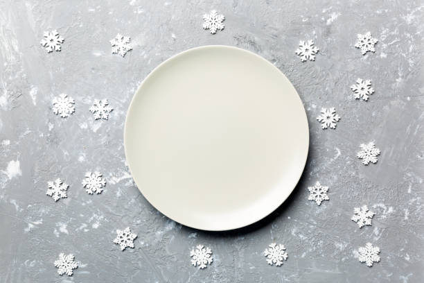 istock Top view of empty plate surrounded with snowflakes on cement background. New Year dinner concept 1186069465