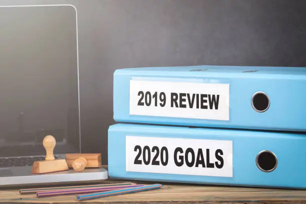 Photo of 2019 review and 2020 goal. Two binders on desk in the office