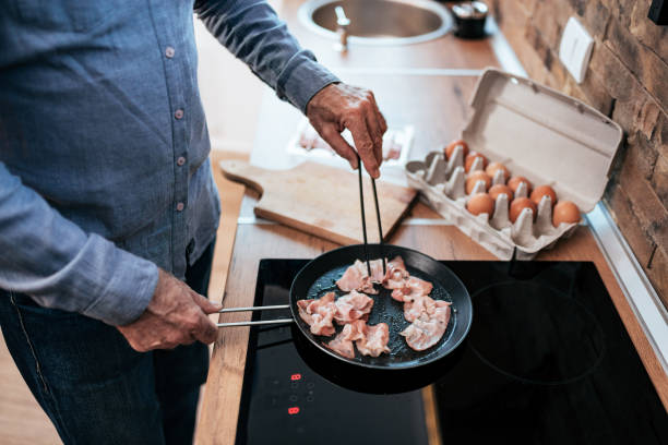 istock Man making delicious home style breakfast with bacon and eggs. 1186078751