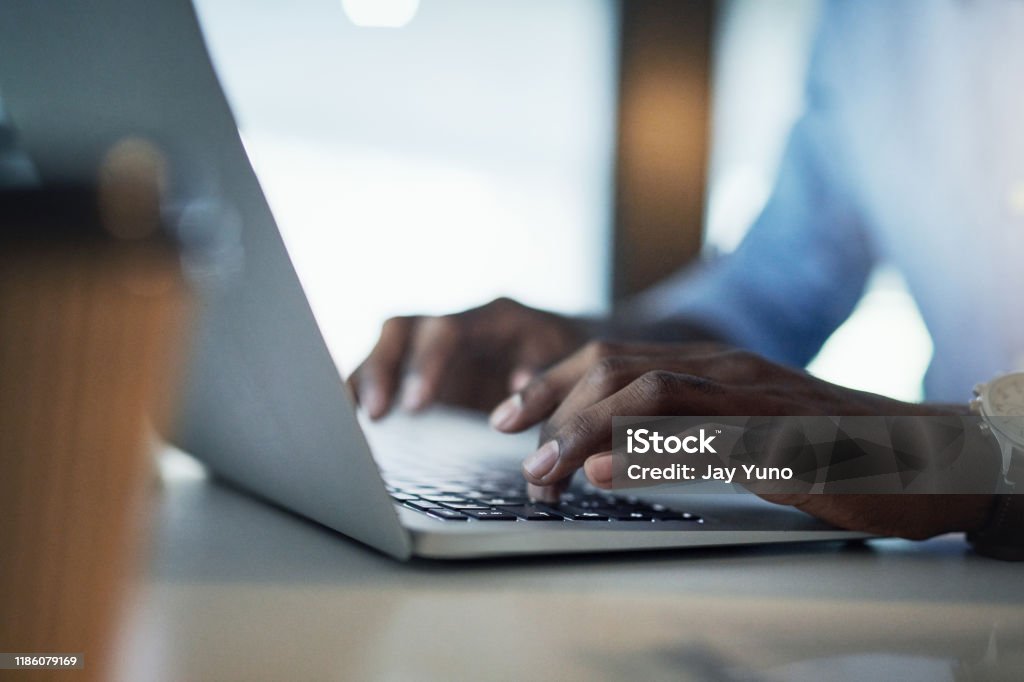 Got to get to those deadlines Closeup shot of an unrecognisable businessman working on a laptop in an office at night Hand Stock Photo