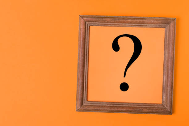 Question mark in a wooden frame on a paper orange background