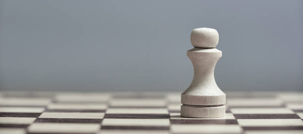 istock One white pawn close-up on a chessboard on a gray background. Background in blur. 1186082858