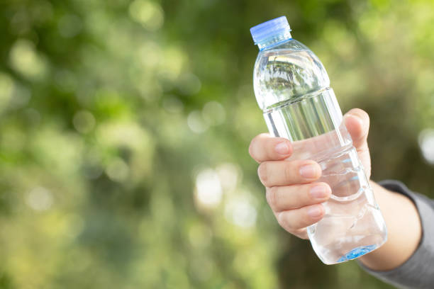 ludzie młodzi ręka trzymająca butelkę świeżej wody pitnej z plastiku w parku. - water human hand people women zdjęcia i obrazy z banku zdjęć
