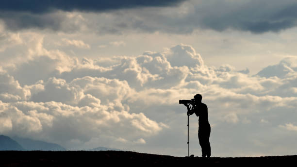 photographer with a mono pod on the mountain and clound