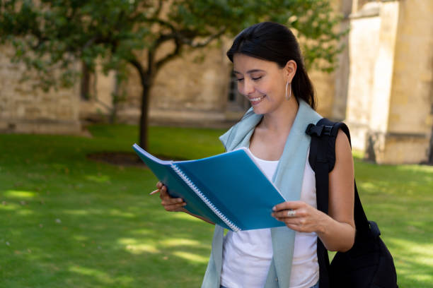 istock Happy female student reading on her notebook outdoors 1186089443