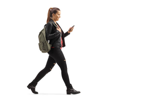istock Girl with a backpack walking and looking at her mobile phone 1186090056