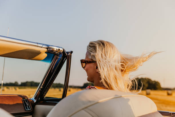 istock Woman in convertible car under clear sky 1186090644