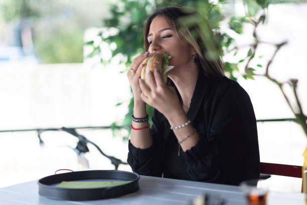 mujer alegre comiendo un sándwich - sandwich turkey gourmet fast food fotografías e imágenes de stock