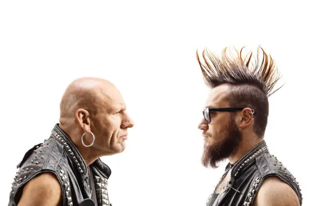 Young punker with a mohawk and an older bald punker looking at eachother isolated on white background