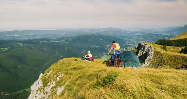 istock Couple cooking and riding bicycle while camping in mountains. 1186093475