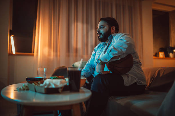 istock Chubby guy watching a basketball match on sofa 1186095154