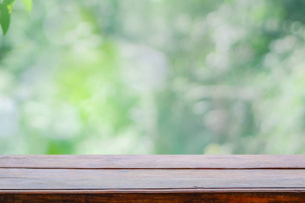istock Empty wooden deck table top on green blurred abstract background from foliage background. Ready used us display or montage products design 1186098871