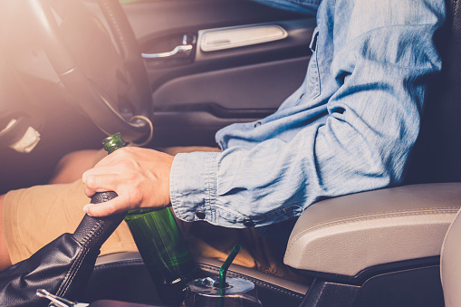 Drinking and driving ,man drinking alcohol and using mobile phone while driving car ,concept drive safely while using a cell phone or drunk alcohol.