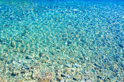 Azure clear sea water. Background of transparent blue sea water top view. Crystal clear water, through the water you can see the bottom.