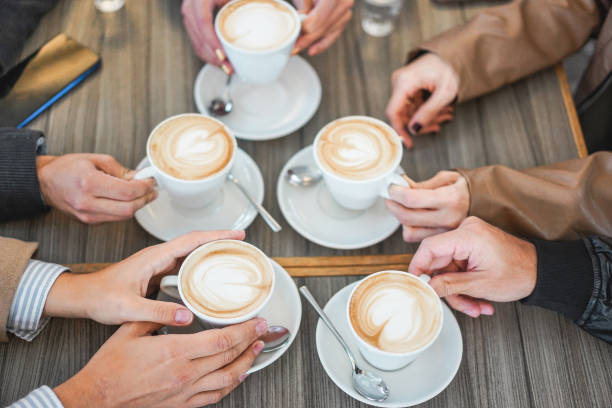 istock People hands view drinking cappuccino inside vintage cafeteria bar - Young friends doing a breakfast during winter season - Bonding and coffee warm beverage concept - Focus on bottom left hand 1186106478