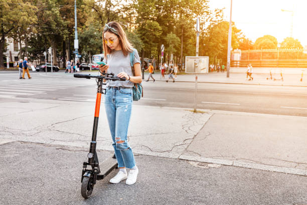 femme utilisant le smartphone et louant le scooter électrique moderne avec une application. concept de transport urbain - location vélo photos et images de collection