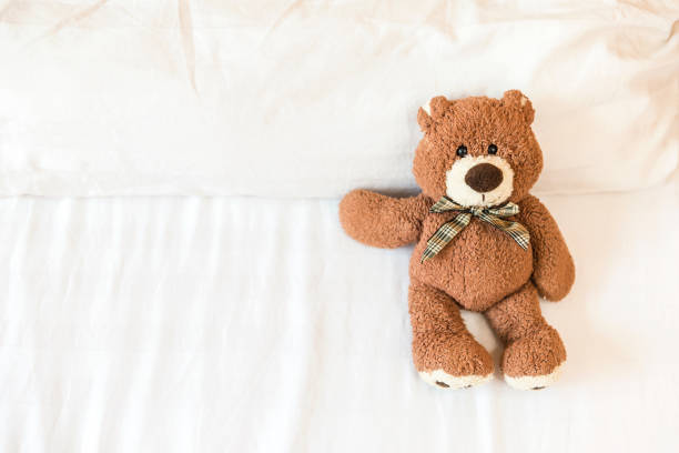 istock Fluffy brown teddy bear lying down on the bed alone 1186107716