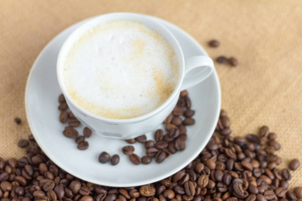 istock foam coffee in a white Cup and coffee beans on the table, selective focus 1186108780