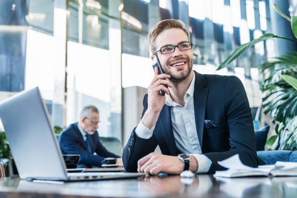 istock Businessman sitting in a restaurant in business center talking on mobile phone while working on laptop 1186110574