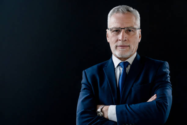 portrait of mature businessman in suit and eyeglasses on black background - old human face men ceo imagens e fotografias de stock