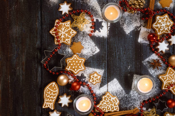 istock Gingerbread cookies, spices and burning candles on a star shape from icing sugar on a dark rustic wooden background, Christmas composition with copy space, high angle view from above 1186116843