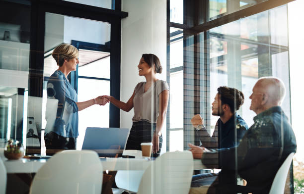 This partnership will bear nothing but success Shot of two businesswomen shaking hands together during a boardroom meeting at work employee introduction stock pictures, royalty-free photos & images