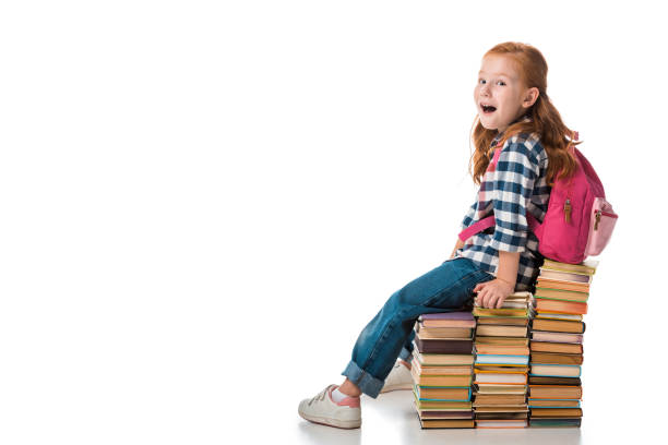 istock surprised redhead schoolkid sitting on books on white 1186117981