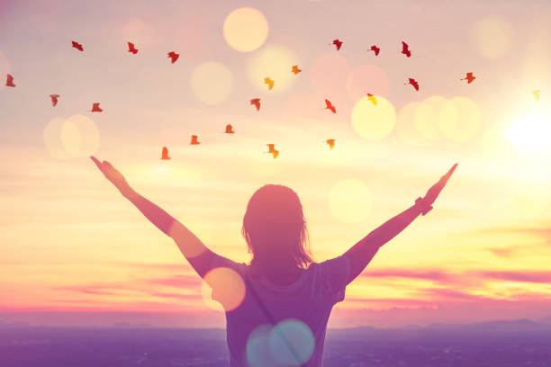 Freedom feel good and travel adventure concept. Copy space of silhouette woman rising hands on sunset sky at top of mountain and bird fly abstract background. Freedom feel good and travel adventure concept. Copy space of silhouette woman rising hands on sunset sky at top of mountain and bird fly abstract background. Vintage tone filter effect color style. joy stock pictures, royalty-free photos & images