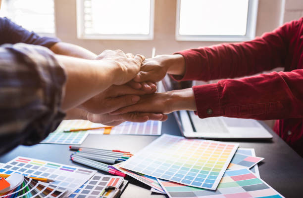 istock Happy graphic designer joining hands in co-working space room workplace. 1186121063
