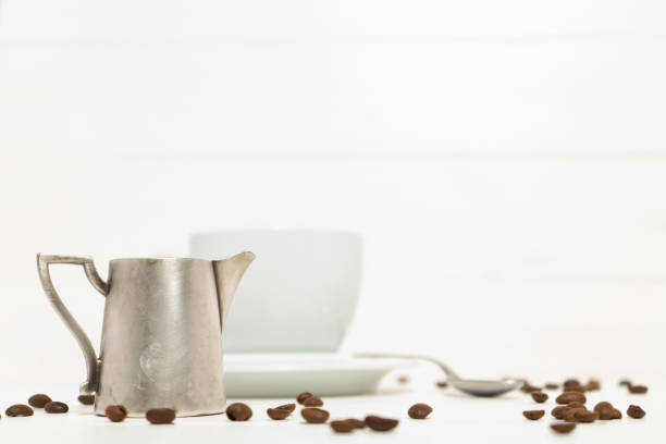 istock Pitcher with milk on the white wooden background. Spoon and  white cup with coffee. 1186123040