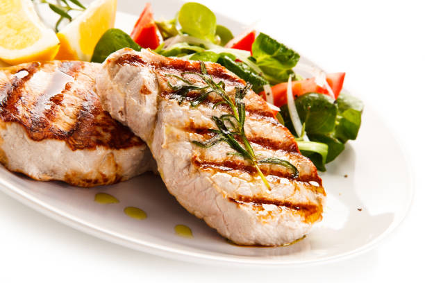 istock Grilled steaks with vegetables on white background 1186125423