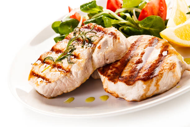 istock Grilled steaks with vegetables on white background 1186125455