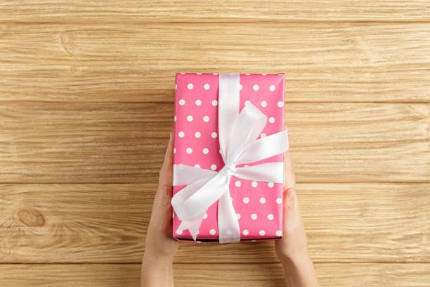 istock gift box in the hands on a wooden background top view 1186127244