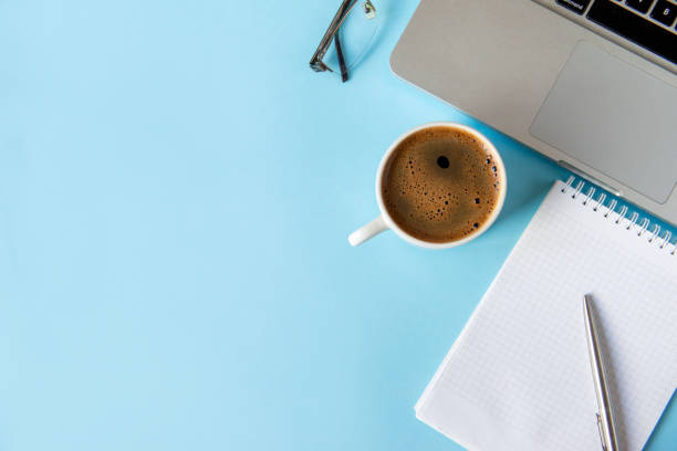 istock 1 notebook with a clean sheet, laptop, pen, black coffee Cup  glasses on a blue background top view, 1186127508