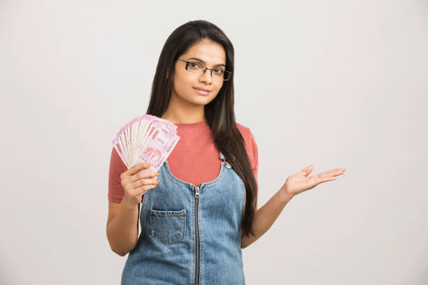istock Young woman holding piggy bank and rupee notes 1186131064