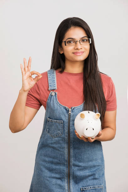 young woman saves money in piggy bank - women savings uk coin imagens e fotografias de stock