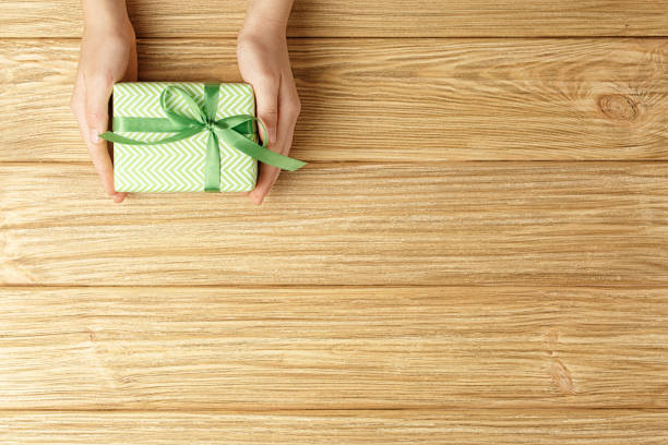 istock gift box in the hands on a wooden background top view 1186132352